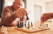 © Theron/peopleimages.com - Senior man, home and chess for games, competition and focus with friends, strategy and problem solving. Elderly person, hands and board for contest with mindset, excited smile and moving at table