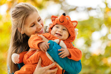 Young Woman And Her Baby Son In Autumn Park, Boy Dressed In Fox Costume