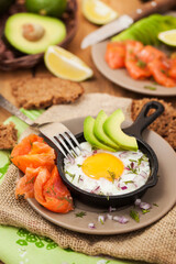 Wall Mural - Fried egg, avocado and smoked salmon in frying pan served for breakfast