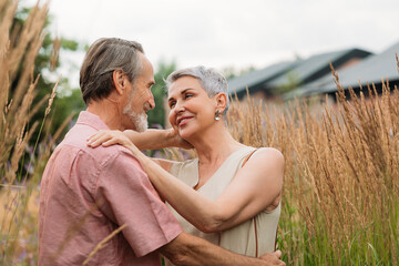 Wall Mural - Two senior people standing together in the field and looking at each other