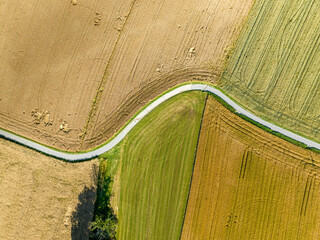Canvas Print - Aerial view of countryside road through fields in rural area in Switzerland.