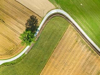 Canvas Print - Aerial view of countryside road through fields in rural area in Switzerland.