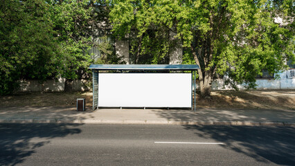 Wall Mural - Big white empty commercial banner mounted at urban stop bus against trees with green foliage. Horizontal billboard with mockup outdoor.