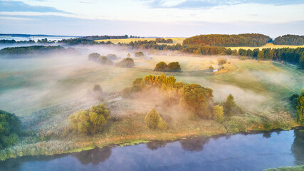 Wall Mural - Aerial view of rural landscape with river and lush trees in fog