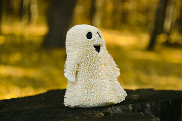 Funny ghost toy stands on an old stump in the autumn forest