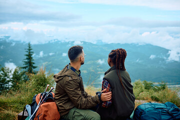 Back view of couple of hikers enjoy in view from top of mountain.