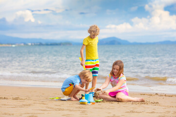 Kids play on tropical beach. Sand and water toy.