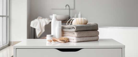 Poster - Stack of towels, cosmetics, loofah and brushes on chest of drawers in bathroom