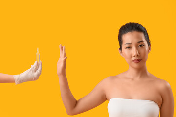 Poster - Beautiful Asian woman rejecting ampule on yellow background. Skin care concept