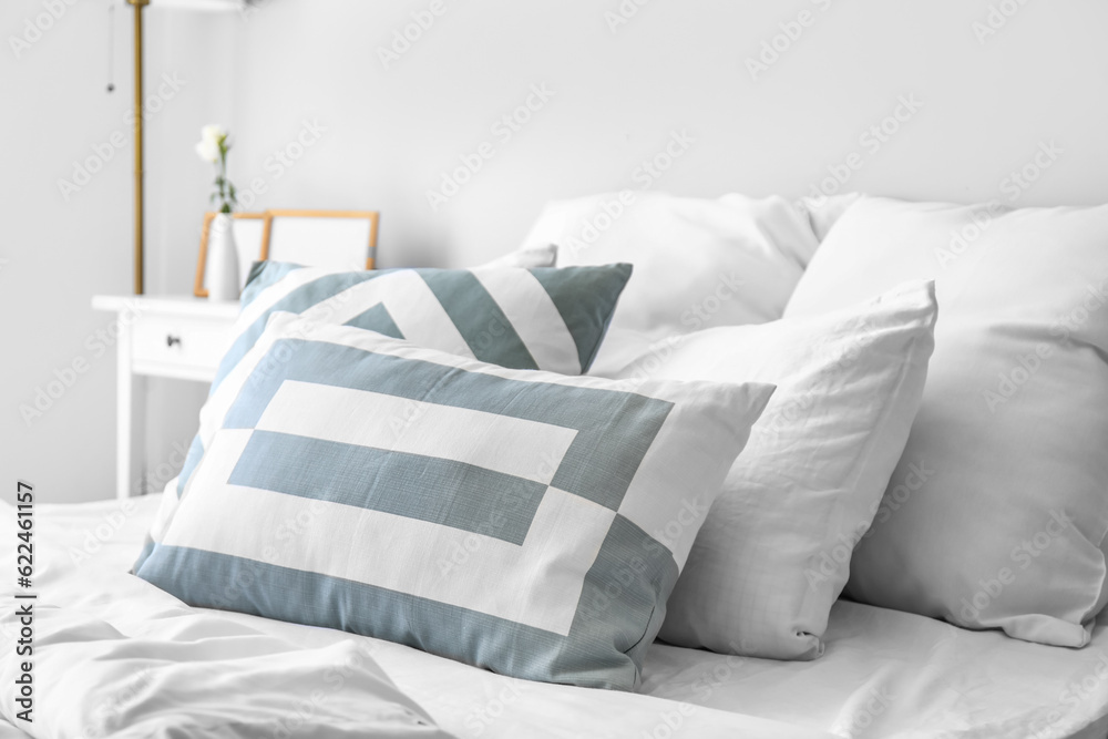Cozy pillows on bed in light room