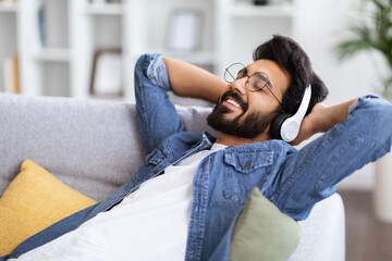 Wall Mural - Handsome Bearded Indian Guy Listening Music In Wireless Headphones At Home