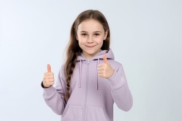 Wall Mural - Cheerful little girl showing thumbs up gesture, isolated on grey background