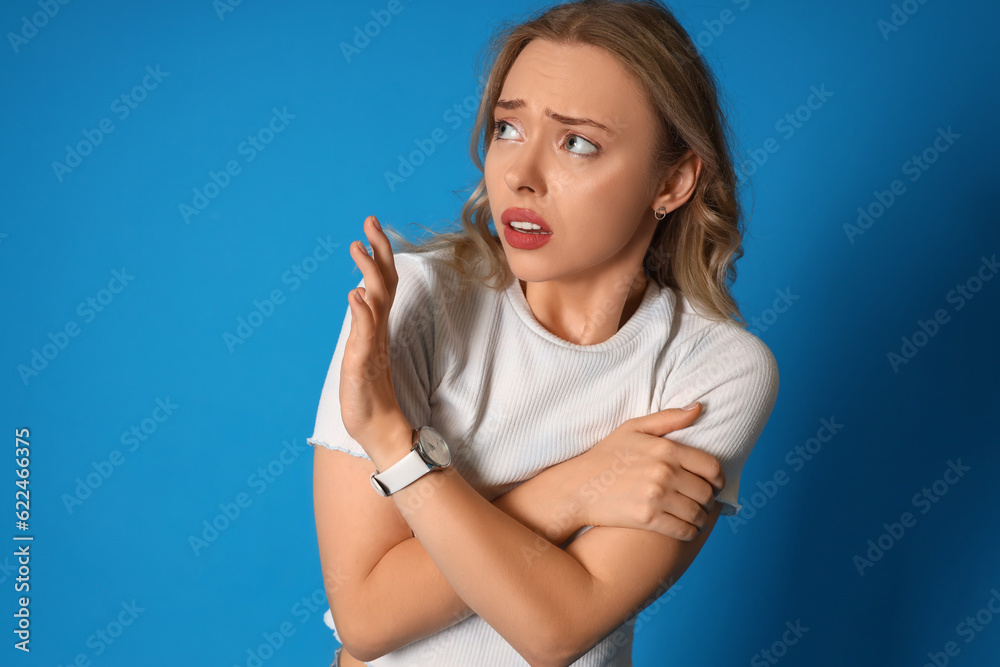 Young woman having panic attack on blue background