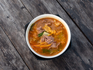 Beef Tomyam, spicy, salty, sour soup, Asian traditional food, in a white bowl on an old wooden table