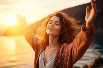 Backlit Portrait of calm happy smiling free woman with open arms and closed eyes enjoys a beautiful moment life on the seashore at sunset 