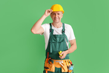 Canvas Print - Mature builder with tape measure on green background