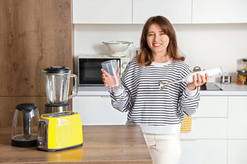 Poster - Young woman with blender in modern kitchen