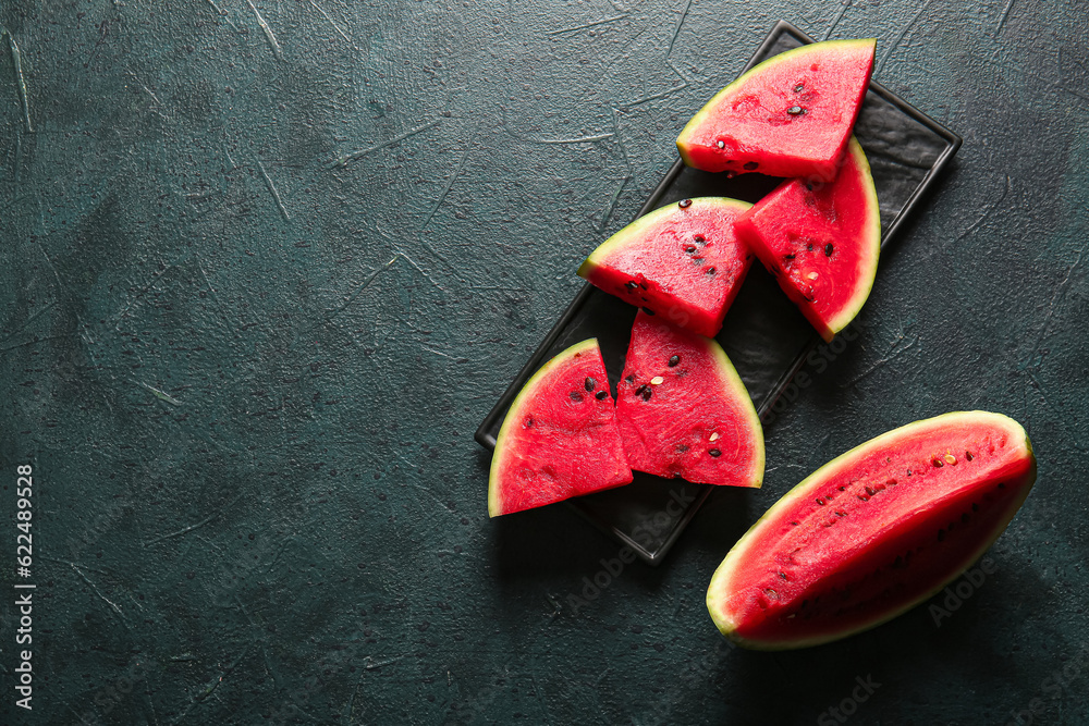 Plate with pieces of fresh watermelon on dark table