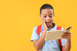 © Pixel-Shot - Surprised little African-American schoolboy with pencil case on orange background