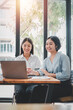 © Satori Studio - Two businesswoman working together on laptop computer. Creative female executives meeting in an office using laptop pc and smiling.