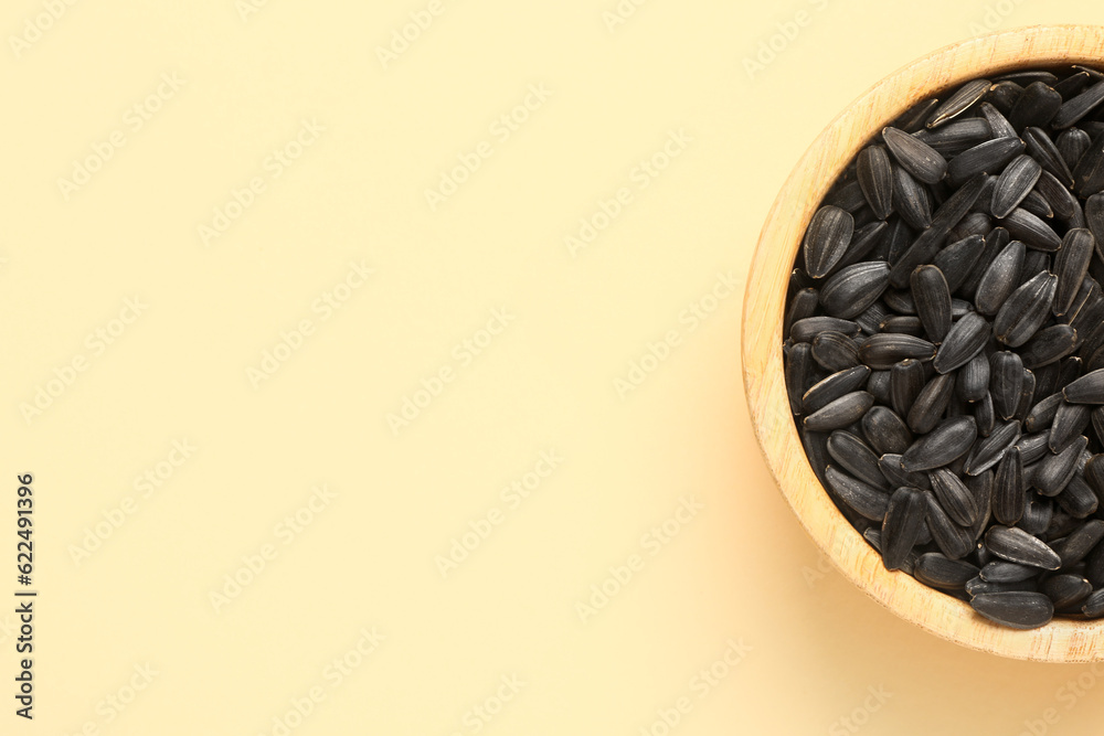 Bowl with sunflower seeds on beige background