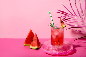 Wall Mural - Glass of tasty watermelon cocktail with mini inflatable ring on pink table near wall