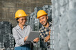 © Odua Images - Asian women and men company employees wearing safety helmets use together a digital tablet in a storage warehouse