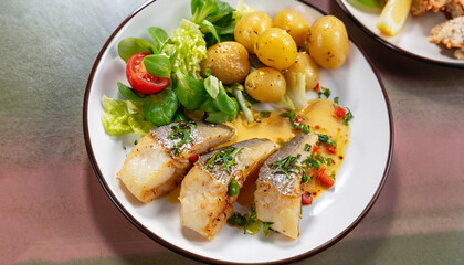 Delicious fillets of pollock or coalfish cooked in a spicy marinade and served with fresh salad and baby potatoes as a seafood appetizer to dinner