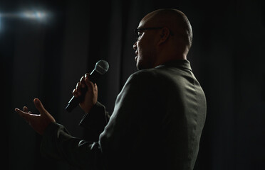 confident successful speaker man talking on stage with spotlight strike through the darkness at corp