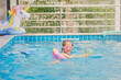 © yAOinLoVE - Cute little Asian 4 years old toddler girl child having fun playing with inflatable swim ring in outdoor swimming pool on hot summer day. Swim devices for toddlers and preschooler concept