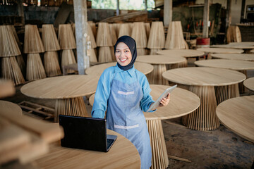 Wall Mural - smiling businesswoman in religious veil work with laptop pc and tablet digital at wood craft workshop