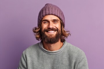 Wall Mural - Portrait of a smiling young man in winter hat looking at camera isolated over violet background
