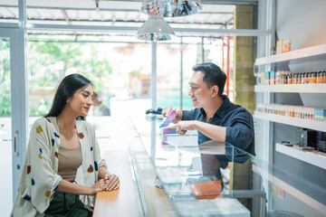 Wall Mural - male shopkeeper offering the variant of vape mod to the female customer