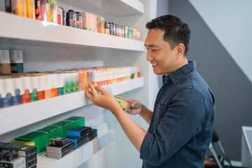 the male shopkeeper taking the e liquid from the shelf