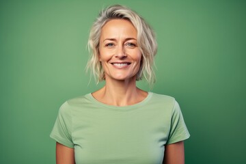 Portrait of smiling middle aged woman looking at camera isolated on green background