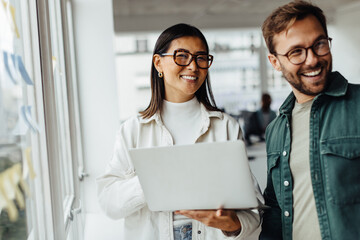 Poster - Business woman holding a laptop and standing with her colleague