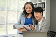 © bongkarn - A smart Asian businessman discussing work and working with a senior businesswoman