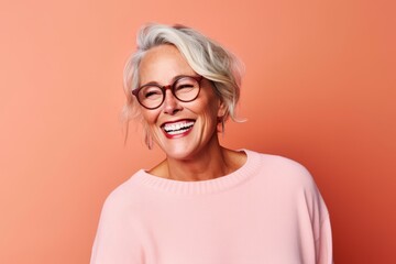 Wall Mural - Portrait of a happy senior woman with eyeglasses against orange background