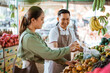 © Odua Images - male seller in apron helping the customer preparing her fruits