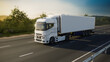 © Haero - a white truck with a trailer drives along the highway against the backdrop of forest and mountains at sunset