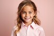 Portrait of a smiling little girl in a pink shirt on a pink background