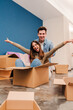 © Jose Calsina - Vertical portrait of young happy couple having fun playing with cardboard box in their new home after moving. Husband and wife arriving at their house with packages enjoying the change. Loan concept