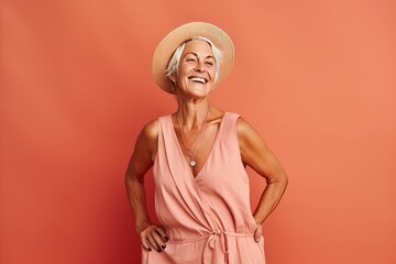 Canvas Print - Portrait of a smiling senior woman in summer hat posing isolated over pink background