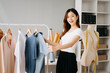 © Nuttapong punna - Asian tailor woman working on clothes in tailoring atelier.  beautiful young female fashion designer smile and after success in modern studio