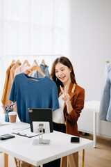 Fashion blogger concept, Young Asian women selling clothes on video streaming.Startup small business SME, using smartphone or tablet taking receive and checking.