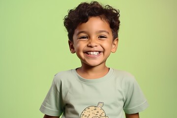 Wall Mural - Portrait of a cute little boy smiling at camera against green background