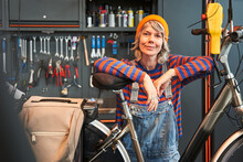 Smiling Woman Technician Posing With Bicycle At Shop Sells