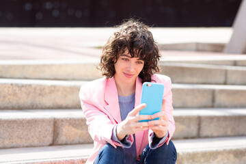 Wall Mural - Fashionable young woman sitting on steps outside using cellphone