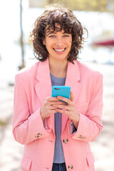 Wall Mural - Pretty young woman with phone smiling outside