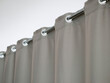 Heavy thick gray curtain with grommets on the stainless tube of the cornice